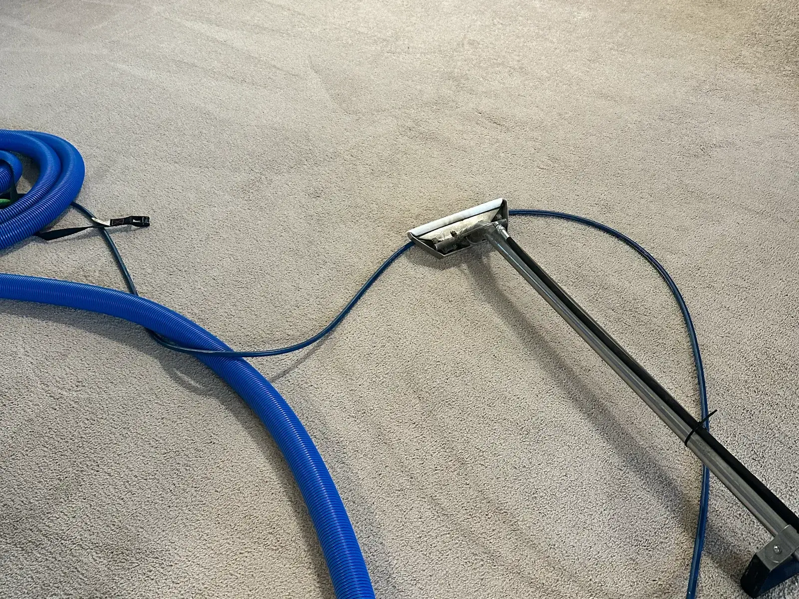 A living room mid-clean, extraction wand and hoses laid across the carpet.